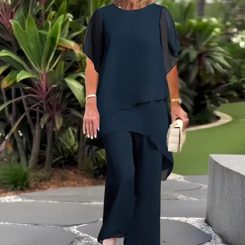 Charmerende sæt med uregelmæssig top og bukser med brede ben – asymmetrisk kant, flagrende dobbeltlag og elegance hele dagen 👗✨