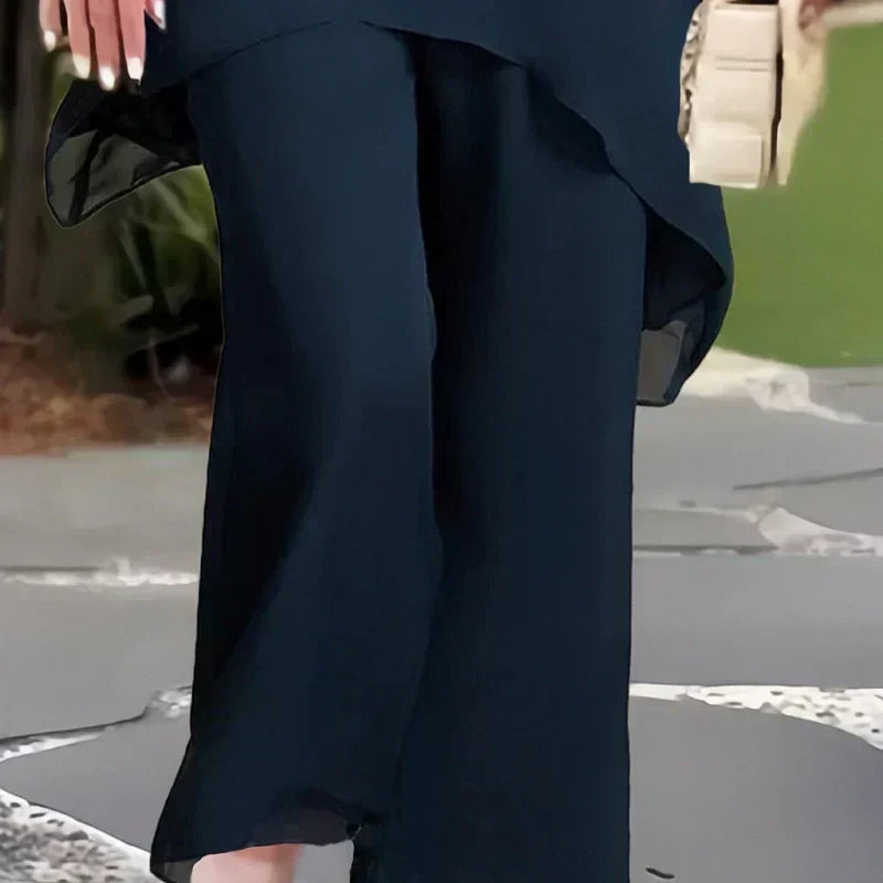 Charmerende sæt med uregelmæssig top og bukser med brede ben – asymmetrisk kant, flagrende dobbeltlag og elegance hele dagen 👗✨